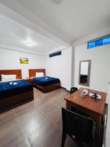 MancosLos Angeles Alojamiento的一间卧室，有两张床、一张书桌和一张桌子