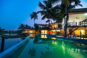 an exterior view of a resort with a swimming pool at night at Mia Riaan Lake View Resort in Ernakulam