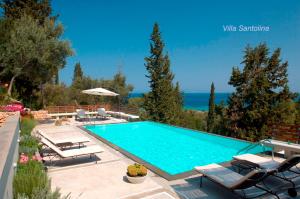 a swimming pool with chaise lounges and chairs and the ocean at Arenaria L. Villas Complex in Lefkada Town