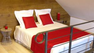 1 dormitorio con 1 cama con almohadas rojas en Millygite Cosy Loft, en Milly-la-Forêt