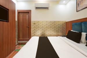 Super Townhouse Kali Ghat Prayagraj Formerly Ramesh Palace في Prayagraj: غرفة نوم مع سرير كبير وتلفزيون +27 صورة