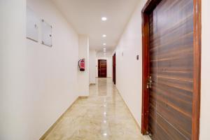 Un pasillo con puerta de madera y un pasillo con paredes blancas. en Collection O High Court Lucknow, en Vibhuti Khand
