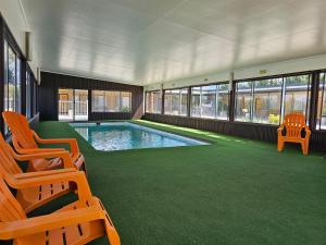 a swimming pool in a building with two chairs and a pool at Majestic Motel in Horsham