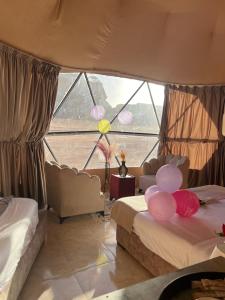a bedroom with two beds and a large window at Queen's Magic Camp in Wadi Rum