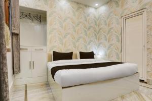 a bedroom with a white bed and a wall at Super Townhouse Vishwanath Temple Varanasi in Varanasi
