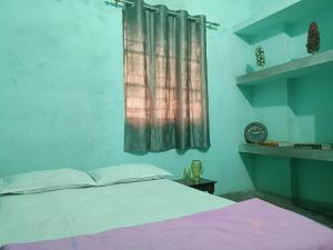 a bedroom with a bed and a window with a clock at santosh lodge in Muzaffarpur