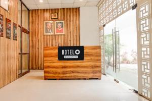 a hotel lobby with a sign on a wooden wall at Hotel O Ashtley Hall Dehradun Formerly Daichi in Dehradun