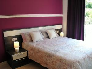 オロットにあるApartament Volcà Garrinadaの紫の壁のベッドルーム1室(大型ベッド1台付)