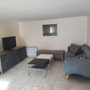 a living room with a couch and a tv at Cozy house, small garden and parking, train station on foot in Orgerus