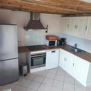 a kitchen with white cabinets and a microwave at Cozy house, small garden and parking, train station on foot in Orgerus