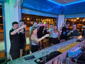 a group of people standing around a bar with drinks at The Hangout Hostel Ao Nang in Ao Nang Beach +24 photos