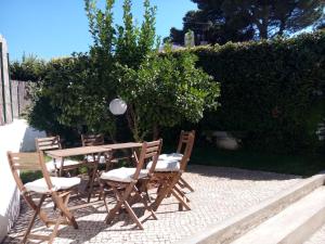 a wooden table and chairs sitting next to a hedge at Apartment Carvalho Araujo in Cascais