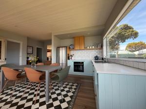 Beach Buoy Opossum Bay في South Arm: مطبخ مفتوح وغرفة طعام مع طاولة وكراسي