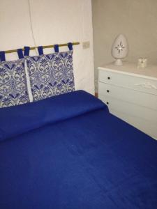 チェーリエ・メッサーピカにあるTrullo Ceglie Messapicaのベッドルーム(青いベッド1台、白いドレッサー付)