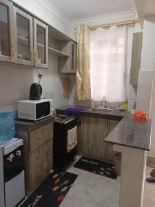 a small kitchen with a microwave and a sink at 1 bedroom BNB Makutano Meru 06 in Meru