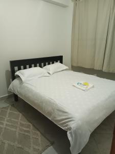 a bed with a white sheets and a book on it at 1 bedroom BNB Makutano Meru 06 in Meru