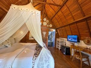 a bedroom with a canopy bed with a desk and a television at Hideout Sunset in Nusa Penida +35 photos