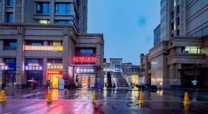 Thank Inn Hotel Hubei Wuhan Caidian Zhong Fa Xincheng Tongji في ووهان: شارع المدينة مع المباني في ليلة ممطرة