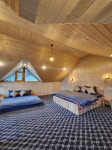 a bedroom with two beds in a wooden ceiling at Winterfell Cottages - Edition Tandi in Jibhi +32 photos