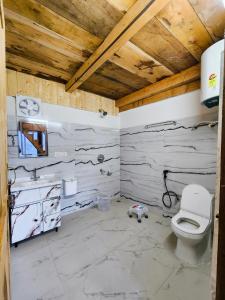 a bathroom with a toilet and a wooden ceiling at Winterfell Cottages - Edition Tandi in Jibhi