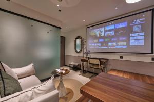 a large screen in a room with a couch and a table at Xiamen Puyiju Movie Theme Hotel in Heshan