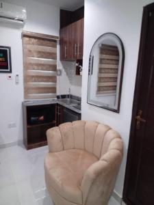 Agape Villa Luxury Apartments في بنين سيتي: غرفة معيشة مع كرسي ومرآة +10 صور