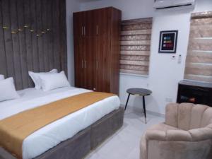 Agape Villa Luxury Apartments في بنين سيتي: غرفة نوم بها سرير كبير وكرسي