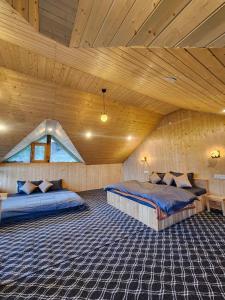 a bedroom with two beds in a wooden ceiling at Winterfell Cottages - Edition Tandi in Jibhi