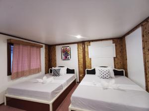 twee bedden in een kamer met witte muren bij Kimura Beachfront Villas El Nido in El Nido