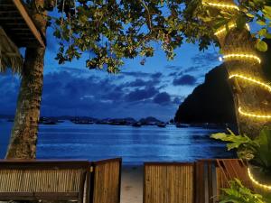 een uitzicht op het water 's nachts met een bankje bij Kimura Beachfront Villas El Nido in El Nido