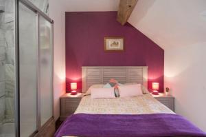 a bedroom with purple walls and a bed with two lamps at les gites du verger in Recey-sur-Ource