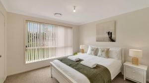 a white bedroom with a bed and a window at The Coastal Corner in Culburra Beach