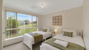 a bedroom with two beds and a large window at The Coastal Corner in Culburra Beach