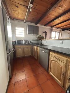 a kitchen with wooden cabinets and a tile floor at La maison des camélias in Le Tampon +7 photos