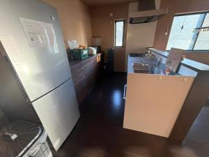 Una cocina con un refrigerador blanco y un fregadero. en 海辺の別荘in竹岡, en Hagyū 10 fotos más