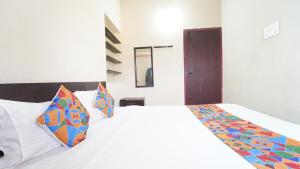 a bedroom with a white bed with colorful pillows at Varun Residency New in Coimbatore