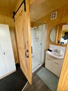a bathroom with a shower and a sink and a door at Watkins Tiny Retreat in Rangiora