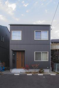 松本Sa one ko松本的停车场里有一栋灰色的房子，门是棕色的