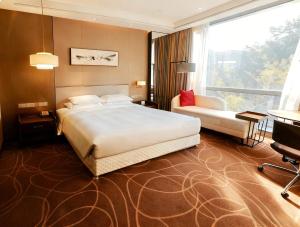 ein Hotelzimmer mit einem großen Bett und einem Stuhl in der Unterkunft Greenland Mansion in Shanghai + 17 Fotos