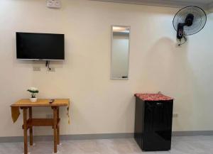 a room with a table and a television on a wall at Piccadilly Green Villas Apartment in Dauis