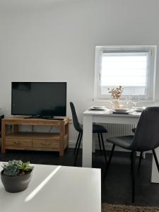 un soggiorno con TV e tavolo con sedie di Ferienwohnung - An der Oder a Barbis