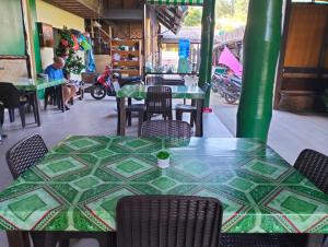 Eddie`s Beach Resort Siargao في جنرال لونا: طاولة وكراسي خضراء في مطعم