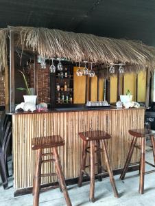 Eddie`s Beach Resort Siargao في جنرال لونا: بار أمامه أربعة كراسي خشبية