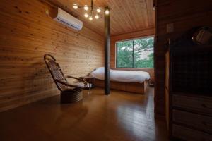 a room with a bed and a chair and a window at 熱海絶景温泉宿 kintsugi 宙 in Wada