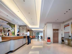 Vienna Hotel Hangzhou East Railway Station West Square في هانغتشو: شخص يقف عند كاونتر في مطعم