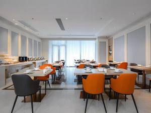 Vienna Hotel Hangzhou East Railway Station West Square في هانغتشو: غرفة طعام مع طاولات وكراسي برتقالية