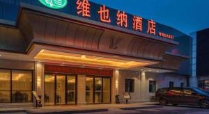 Vienna Hotel Shanghai Hongqiao National Exhibition Center Fengxi Beiqing Road في Fengxi: مبنى به سيارة متوقفة أمامه