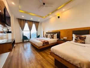 Pine Rock Hotel in Mussoorie Peaceful Stay في موسوري: غرفة فندقية بسريرين وتلفزيون