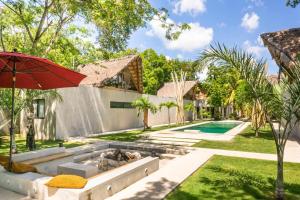 a backyard with a swimming pool and a red umbrella at Tulum Private Villa, Weddings, Retreats, Groups in Tulum
