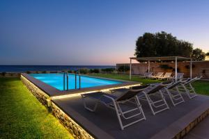 a swimming pool with lounge chairs next to a pool at Sea Homes Villas-Villa Sylvia in Kiotari